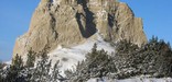 Snow-covered Badlands butte and juniper trees rise to meet the day